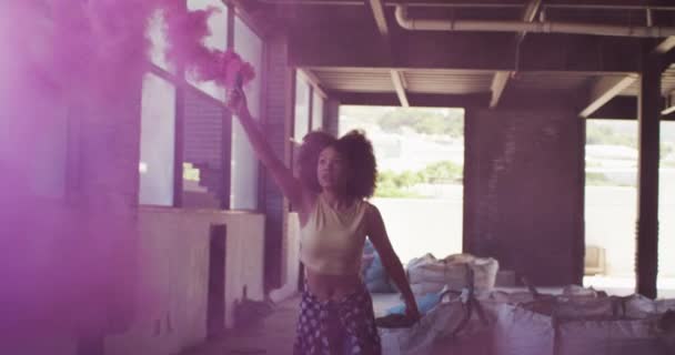 Mieszane rasa kobieta gospodarstwa fioletowy flara działa przez w pusty budynek — Wideo stockowe