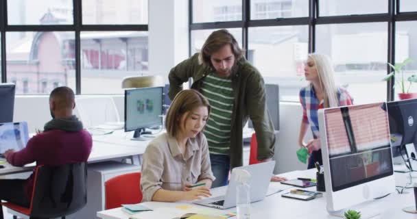 Divers hommes d'affaires utilisant des ordinateurs portables passant par la paperasserie dans le bureau moderne — Video