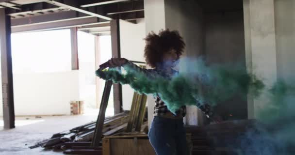 Mulher de raça mista segurando flare verde dançando em um prédio vazio — Vídeo de Stock