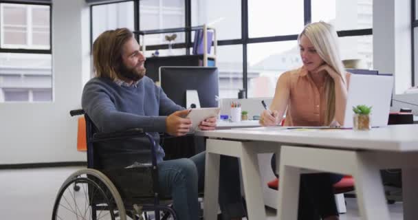 Engelli beyaz iş adamı tekerlekli sandalyede oturup dijital tablet kullanarak iş arkadaşıyla konuşuyor. — Stok video