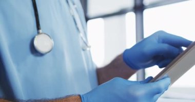 Beyaz erkek doktor koruyucu eldiven giyip dijital tablet kullanıyor. Coronavirus covid 19 salgını sırasında tıbbi profesyonel sağlık çalışanı hijyeni.