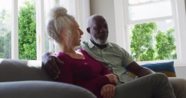 Karışık ırk son sınıf çifti evdeki kanepede otururken birbirlerini yiyorlar.