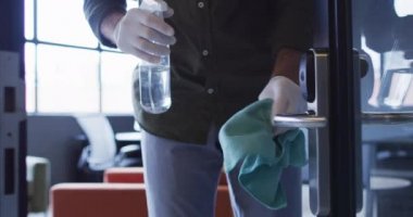 Modern ofis alanlarını temizleyen koruyucu kıyafetler giyen ofis temizleyicileri.