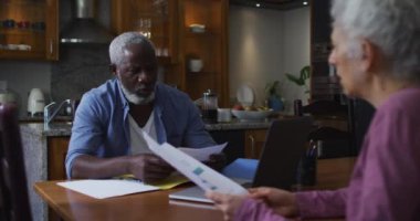 Karışık ırk son sınıf çifti evde finansman tartışıyor ve hesaplıyor.