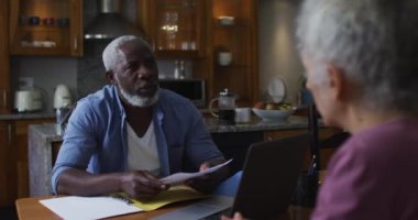 Karışık ırk son sınıf çifti evde finansman tartışıyor ve hesaplıyor.