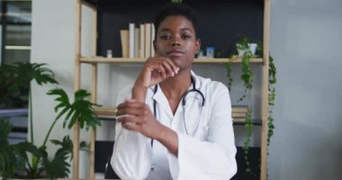 Afro-Amerikan kadın doktor portresi. Görüntülü konuşma yapıyor. Dinliyor ve kameraya bakıyor.