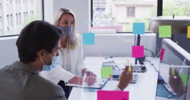 Yüz maskesi takan çeşitli iş arkadaşları ofiste konuşan bilgisayarlar kullanıyor. İş yerinde hijyen, covid 19 koronavirüs salgını sırasında sosyal mesafeler..