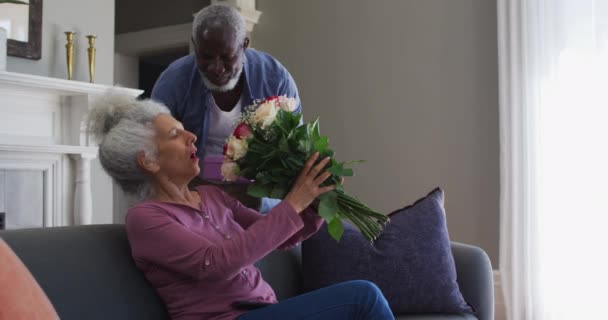 Africano americano homem sênior dando caixa de presente e buquê de flores para sua esposa em casa — Vídeo de Stock