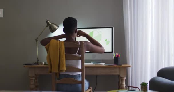 Вид сзади на африканскую американку, вытягивающую руки с помощью компьютера во время работы из дома — стоковое видео