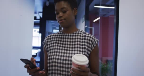 Afro-Amerikaanse zakenvrouw met koffiekop lopen in kantoor gang — Stockvideo