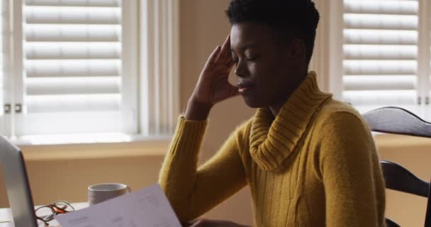 Стресс африканской американки, держащей документ во время работы из дома — стоковое видео