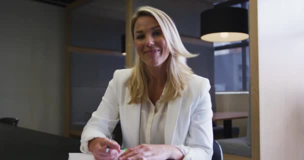 Caucásico mujer de negocios teniendo video chat pasando por el papeleo en la oficina moderna — Vídeos de Stock