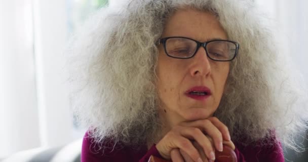 Старшая белая женщина держит трость, сидя дома на диване. — стоковое видео