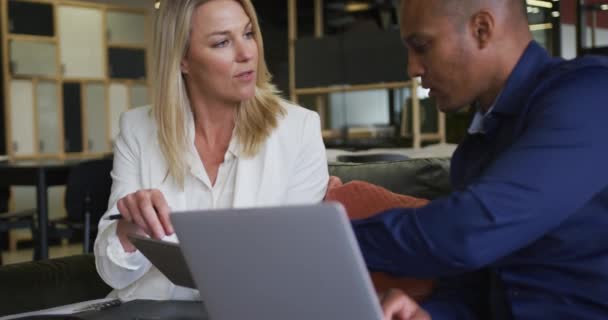 Dois colegas de negócios diversos usando laptop e discutindo em uma reunião casual — Vídeo de Stock
