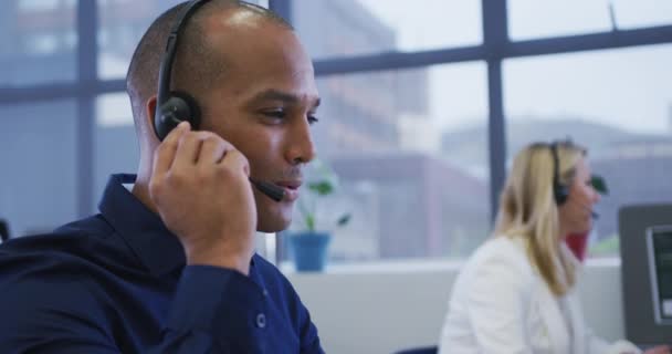 Diverse zakenmensen zitten met behulp van computers praten met telefoon headsets — Stockvideo