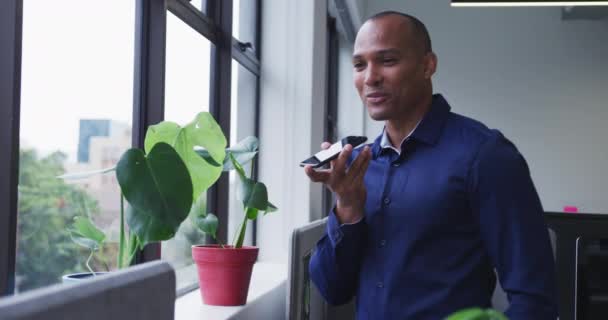 Mieszany Biznesmen Wyścigowy Rozmawiający Smartfonie Wyglądającym Przez Okno Biurze Komunikacja — Wideo stockowe