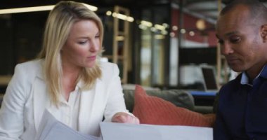 İki farklı iş arkadaşı bilgisayarda kağıt işlerini tartışıyor ve sıradan toplantılarda gülümsüyor.