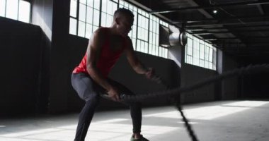 Afrika kökenli Amerikalı bir adam boş bir şehir binasında savaş halatları kullanıyor.