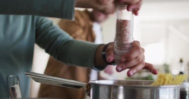 Çok ırklı eşcinsel erkek çift mutfakta yemek hazırlıyor.