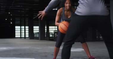 Afrika kökenli Amerikalı kadın ve erkek boş bir binada durup basketbol oynuyorlar.