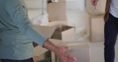 Çoklu etnik kökenli eşcinsel erkek çift, bir evin anahtarlarını kucaklıyor.