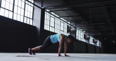 Afrikalı Amerikalı kadın boş bir şehir binasında atlama egzersizleri yapıyor.