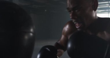 Afrika kökenli Amerikalı bir adam boks eldiveni giyip kum torbası yumruklama eğitimi alıyor. şehir sporu, fitness ve sağlıklı yaşam tarzı.