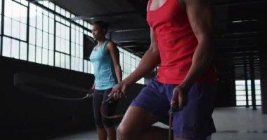 Afrika kökenli Amerikalı kadın ve erkek boş bir şehir binasında ip atlıyorlar.