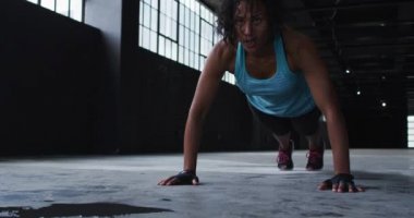 Afrikalı Amerikalı kadın boş bir şehir binasında şınav çekiyor.