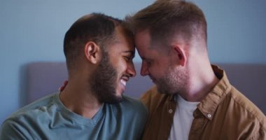 Çok ırklı eşcinsel çift kucaklaşıyor ve gülümsüyor.