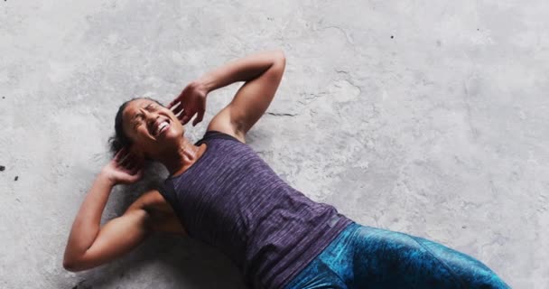 Africano americano mulher fazendo crunches no chão em um vazio urbano edifício — Vídeo de Stock