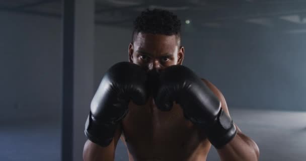 Afro-Américain portant des gants de boxe formation jetant des coups de poing dans la pièce vide — Video