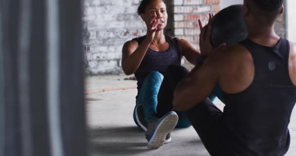 Africký Američan muž a žena cvičení s medicínou míč v prázdné městské budově — Stock video