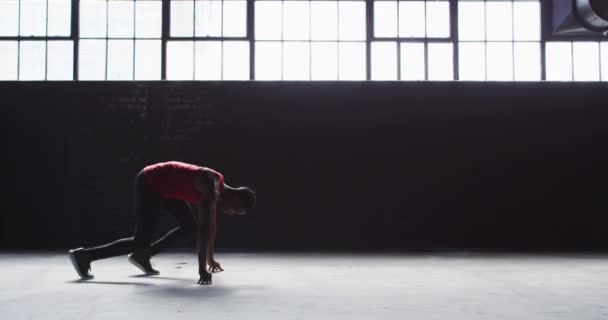 Africano americano ajoelhado começando uma corrida em um prédio vazio — Vídeo de Stock