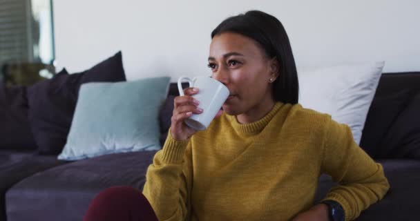 Mujer de raza mixta sentada en el suelo bebiendo una taza de café — Vídeos de Stock