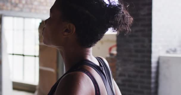 Afrikansk amerikansk kvinna vilar efter träning stående i tom stadsbyggnad — Stockvideo