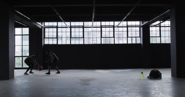 Afrikansk amerikansk man och kvinna står i en tom byggnad och spelar basket — Stockvideo