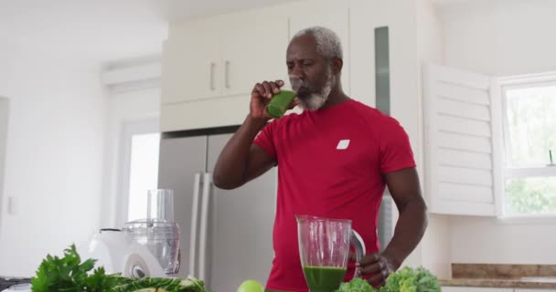 高齢のアフリカ系アメリカ人男性が自宅で果物や野菜の健康飲料を飲んでいます 老人ホームでの健康フィットネス — ストック動画