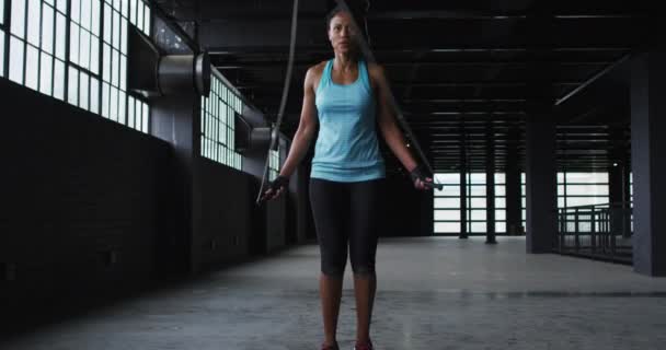アフリカ系アメリカ人の女性がロープを空の都市の建物の中で飛ばしてる 都会のフィットネスや健康的なライフスタイル — ストック動画