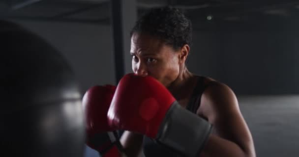 Afrikansk amerikansk kvinde iført boksehandsker træning i tom bygning stansning punchbag – Stock-video