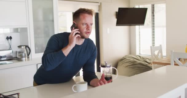 Caucásico hombre hablando en un teléfono inteligente en la cocina — Vídeo de stock