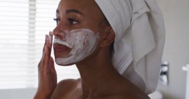 Banyoya yüz maskesi takan Afro-Amerikan kadını yakın çekim.