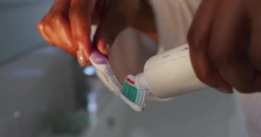 Afrikalı Amerikalı kadının banyoda diş fırçasına diş macunu sürüşünü yakından çek.