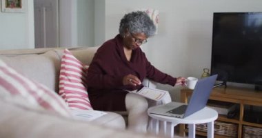 Kıdemli Afro-Amerikan kadın kahve içerken evdeki mali durumları hesaplıyor.