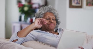 Saygıdeğer Afro-Amerikan kadın dijital tablette bir video görüşmesi yaparken el sallıyor ve öpüşüyorlar.