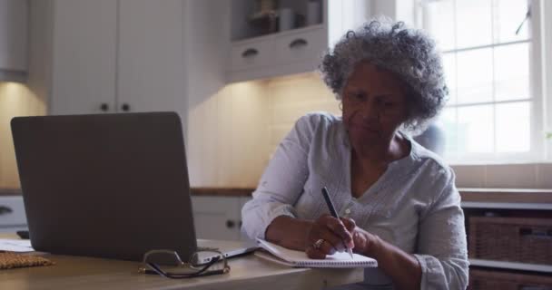シニアアフリカ系アメリカ人女性のラップトップを使用し、自宅でメモを取る — ストック動画