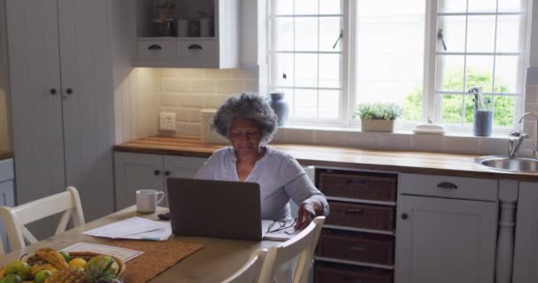 Mujer afroamericana mayor usando laptop y calculando las finanzas en casa — Vídeos de Stock