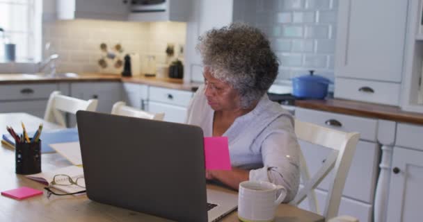 Старшая американка из Африки приклеивает записки на свой ноутбук дома — стоковое видео