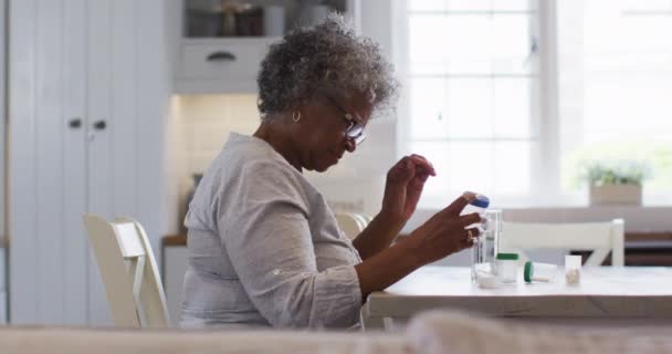Starsza Afroamerykanka patrzy na pusty pojemnik z lekami siedząc w domu — Wideo stockowe
