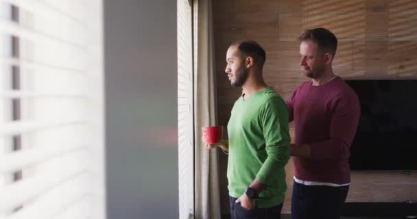 Мультинациональная гей-пара пьет кофе и обнимает — стоковое видео